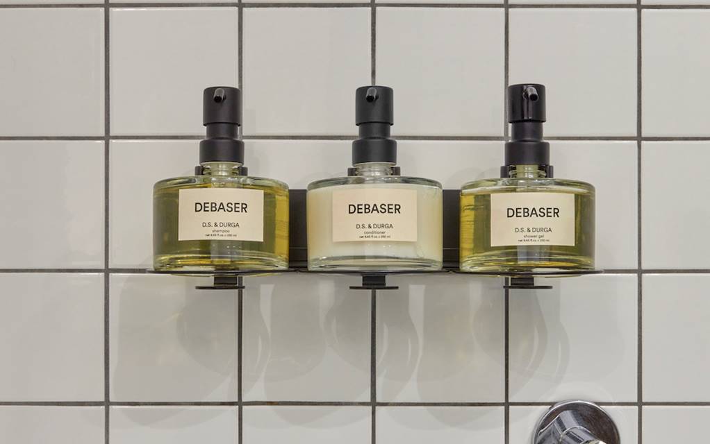 Three bottles of soap arranged neatly on a bathroom shelf, showcasing various colours and designs.