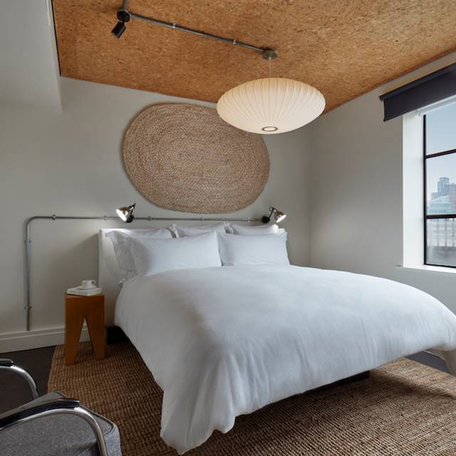 A serene bedroom featuring a white bed positioned near a window, allowing natural light to illuminate the space.