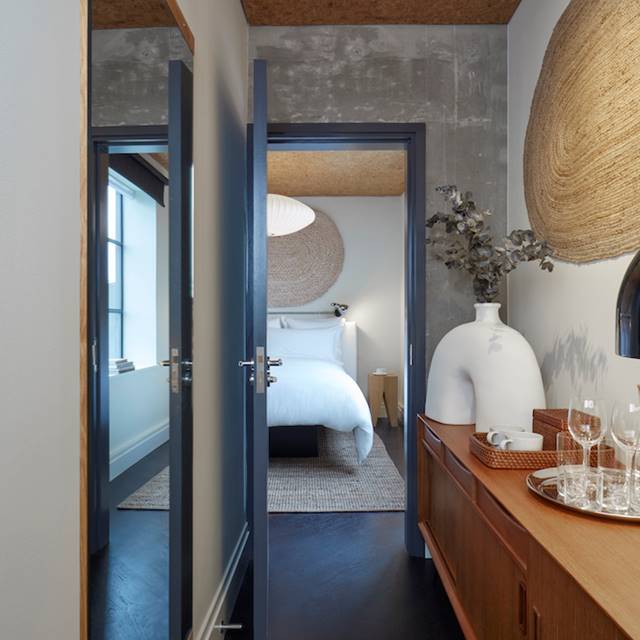 A modern and minimalist London hotel bedroom at One Hundred Shoreditch with white linens, natural decor, and soft lighting.