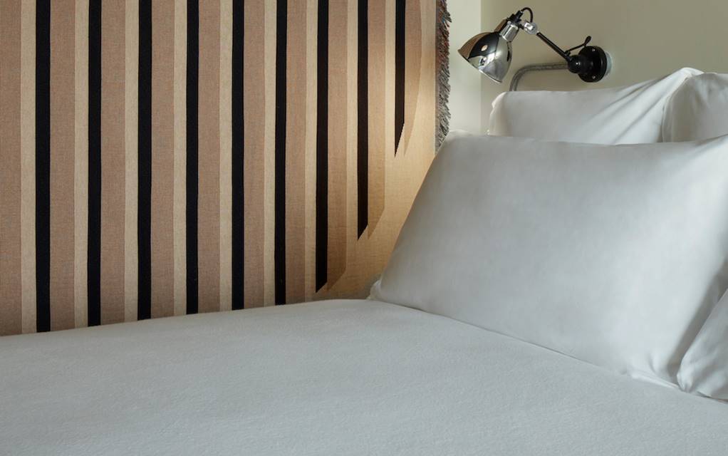A neatly made bed featuring crisp white sheets and fluffy pillows, creating a serene and inviting atmosphere.