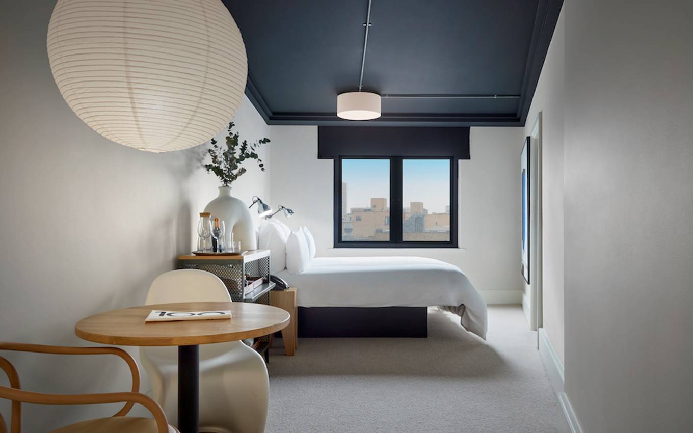 An inviting bedroom with a well-arranged bed, a functional table, and a lamp enhancing the ambiance.