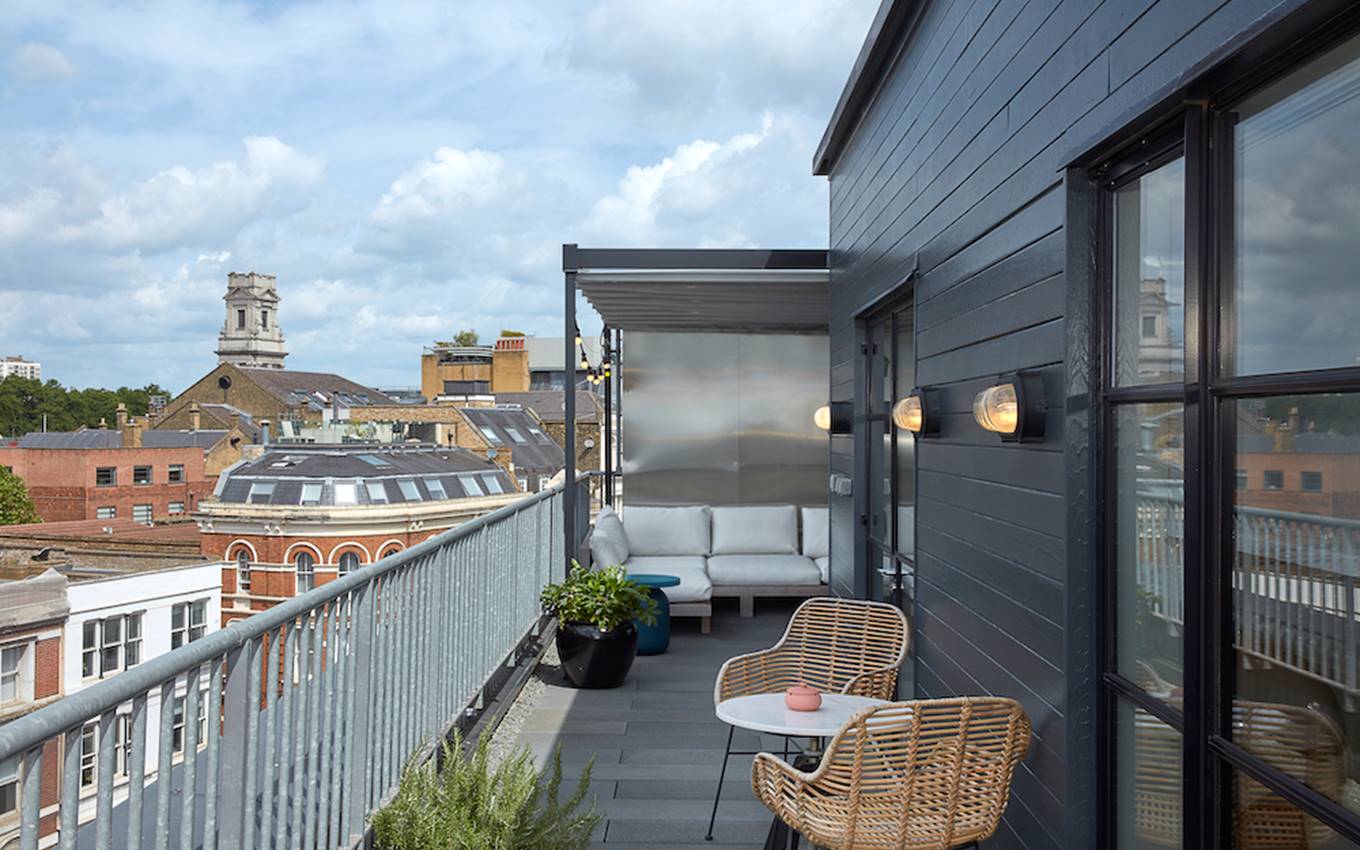 A balcony adorned with wicker chairs provides a picturesque view of the bustling city below.