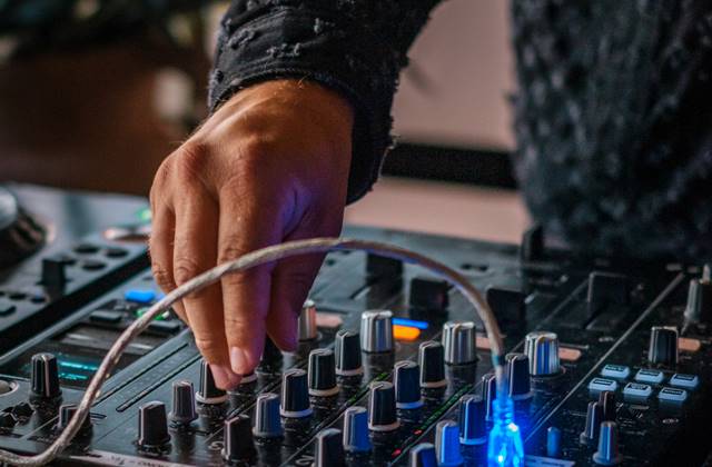 A DJ skilfully mixing music on a professional DJ mixer, creating an energetic atmosphere at an event.