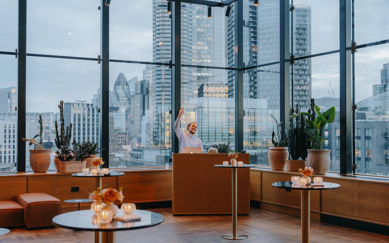 A well-lit room containing tables and chairs set before large windows, enhancing the space with natural illumination.