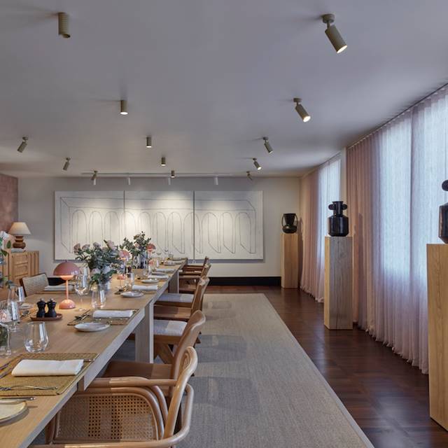 A spacious dining room featuring a long table surrounded by elegant chairs, ready for gatherings and meals.