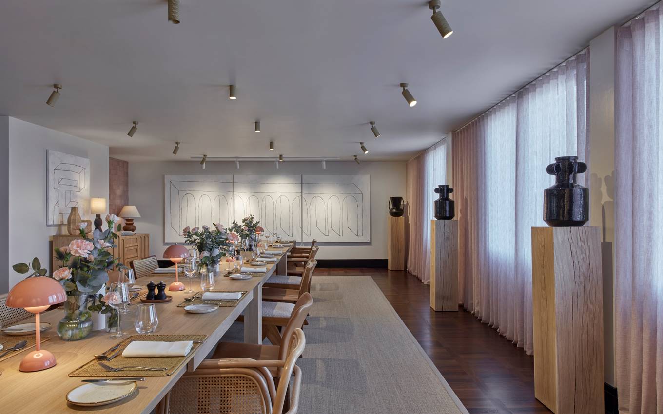 A spacious dining room featuring a long table surrounded by elegant chairs, ready for gatherings and meals.