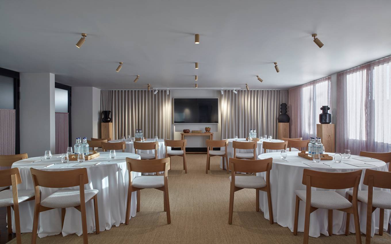 A stylish dining area with a long wooden table set for a meal, surrounded by elegant chairs and warm lighting.