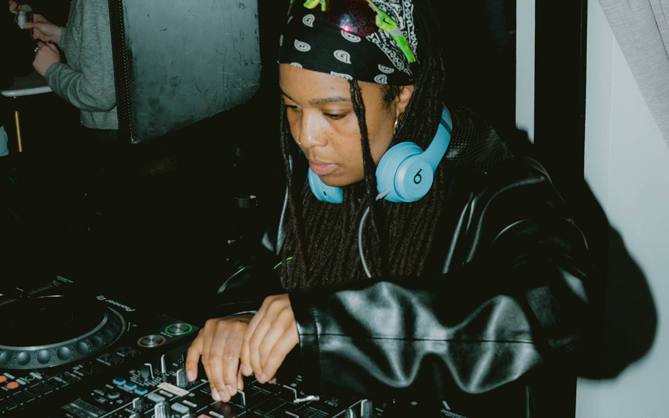 A woman with wearing headphones, skilfully mixing music at a DJ booth creating a lively atmosphere.
