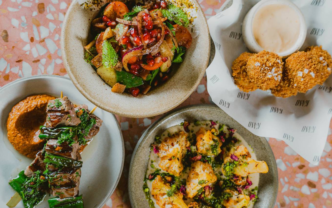 A colourful spread of Middle Eastern-inspired dishes, including skewers, crispy bites, salad, and roasted cauliflower.