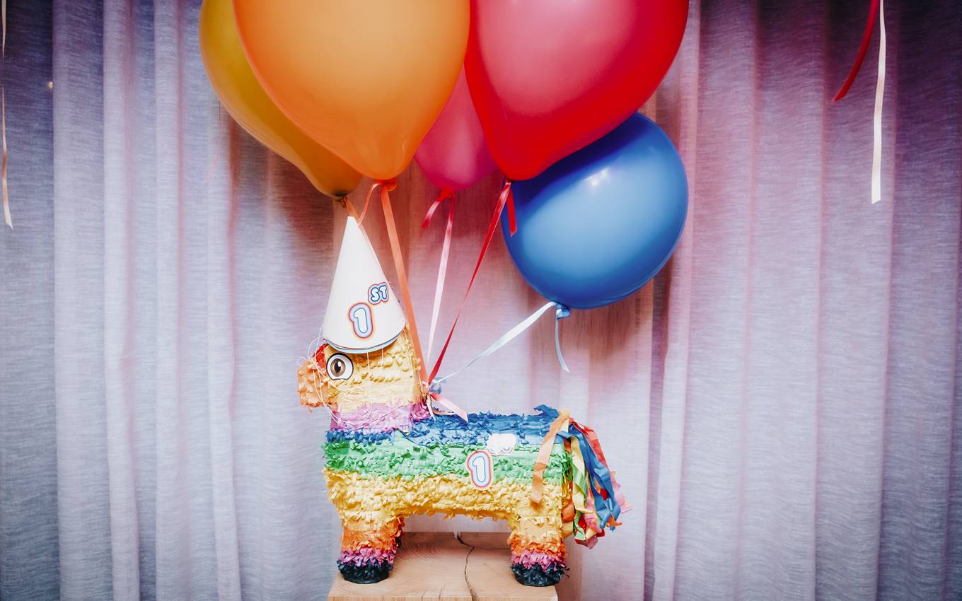 A vibrant pinata adorned with balloons and a festive party hat, perfect for a celebratory occasion.