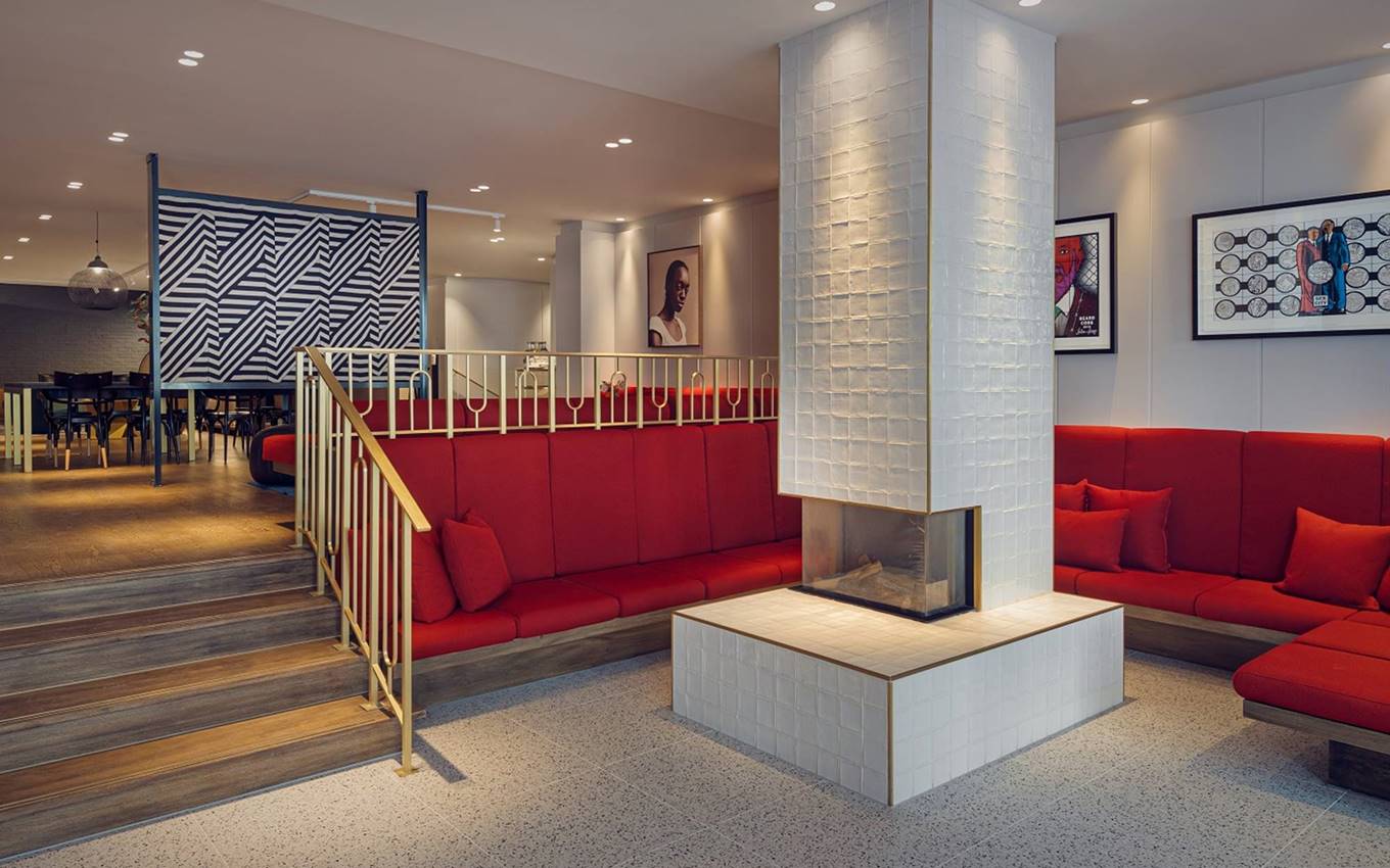 Elegant hotel lobby at Kimpton de Witt with red seating, a central white-tiled fireplace, and art-adorned walls.