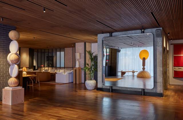 A spacious and inviting hotel lobby featuring a large mirror and elegant wooden flooring.