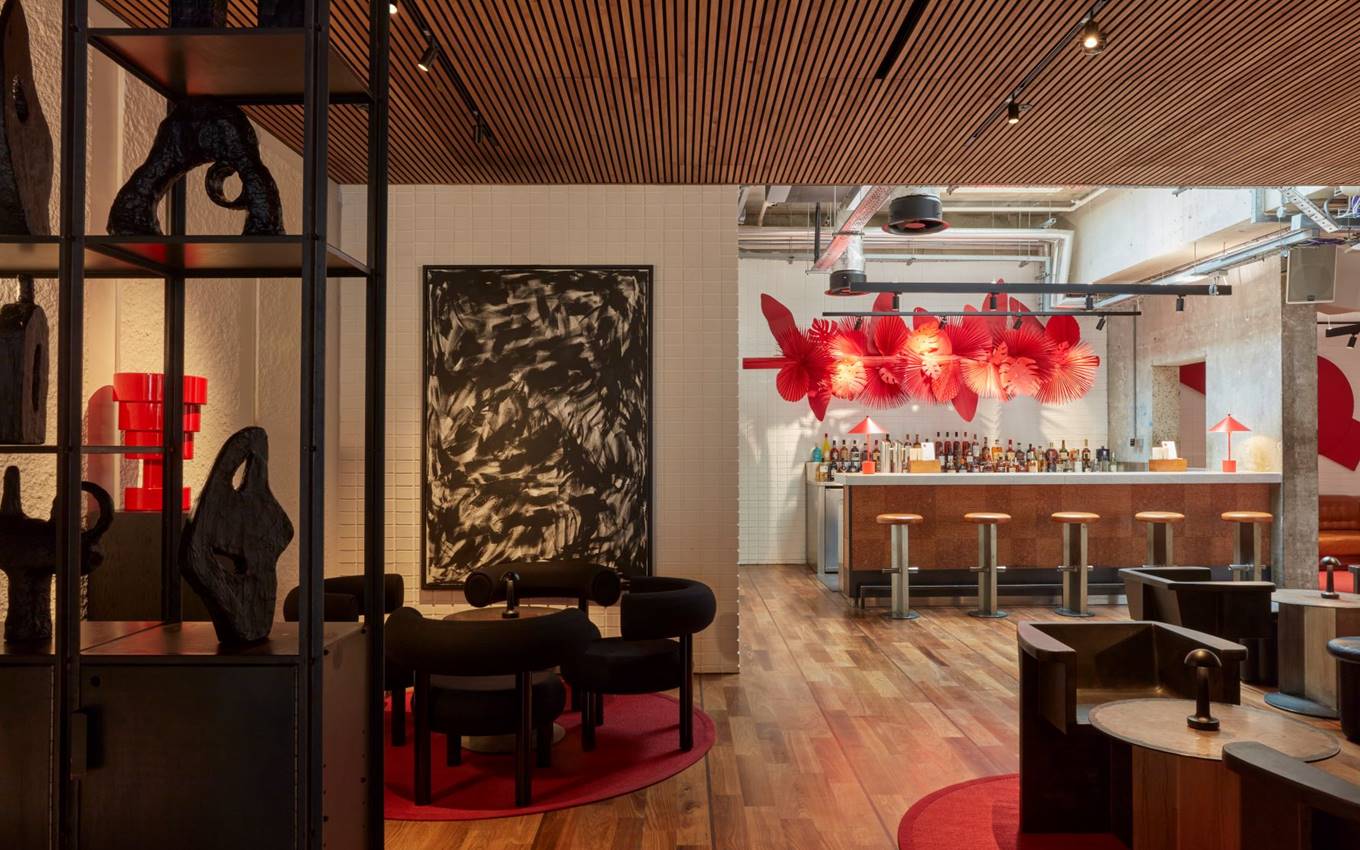 Modern London bar area with wooden floor, red decor accents, and artful lighting featuring abstract black and red wall art.