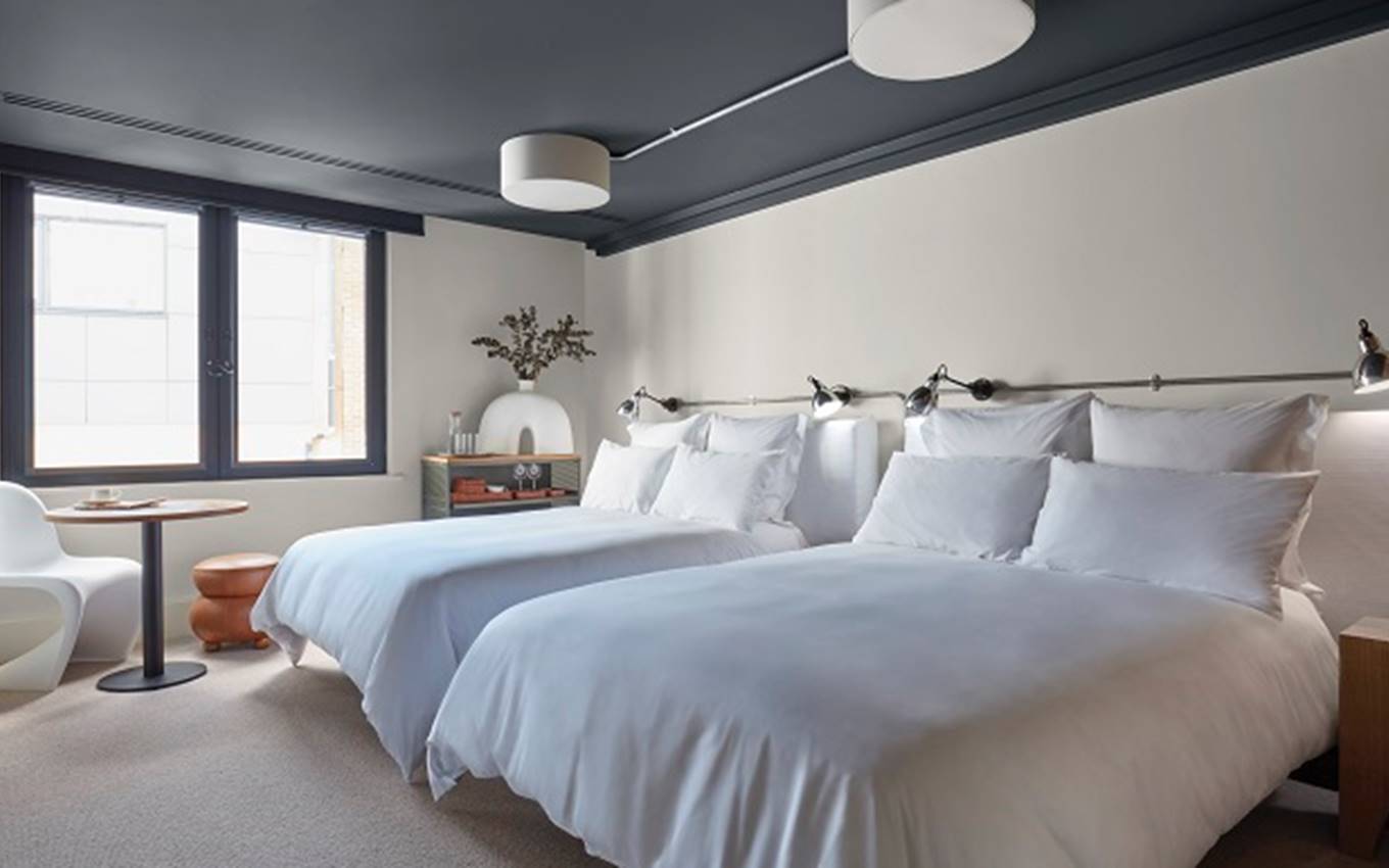 A room featuring two beds with white sheets, complemented by blue walls, creating a serene and inviting atmosphere.