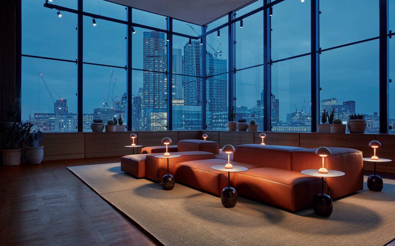 An elegant and cosy room featuring a stunning nighttime city skyline view through large windows.