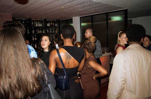 A diverse group of individuals socializing and enjoying drinks together in a lively bar setting.