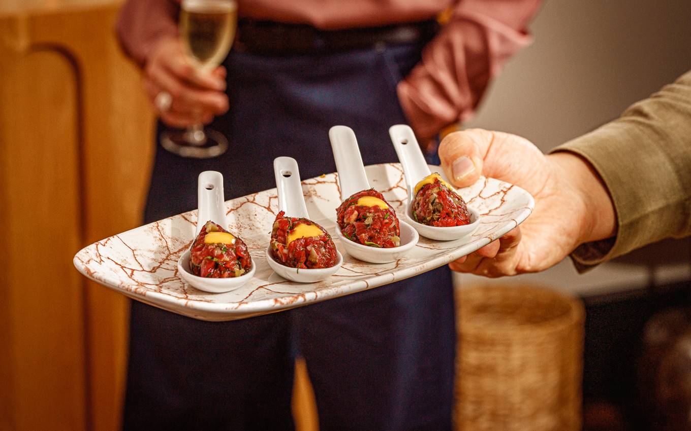 Four appetisers on porcelain spoons, garnished with a yellow sauce, served on a marbled tray at a London restaurant.