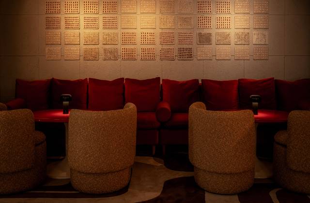 A welcoming restaurant interior featuring red couches and a wall adorned with various pictures.