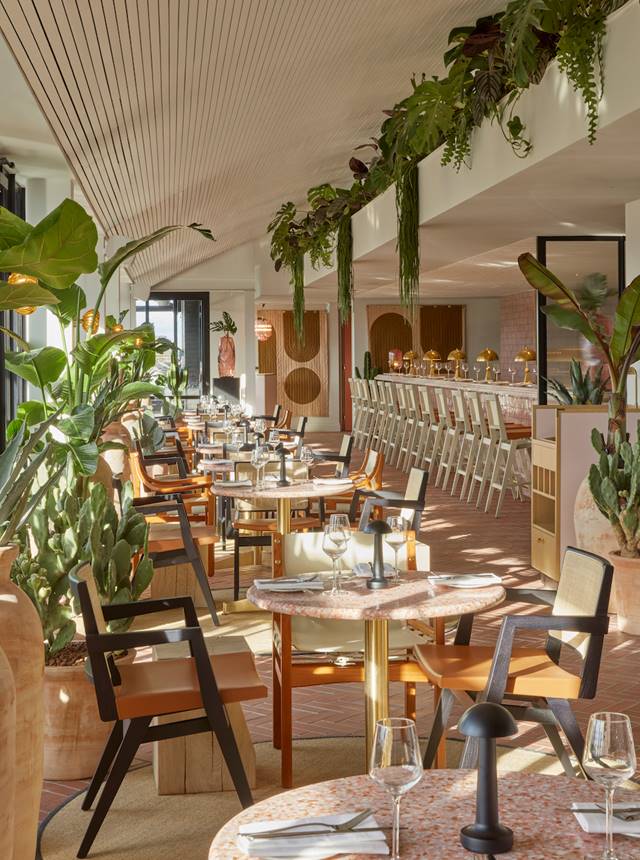 Bright and plant-filled dining area at One Hundred Shoreditch with set tables and modern decor.