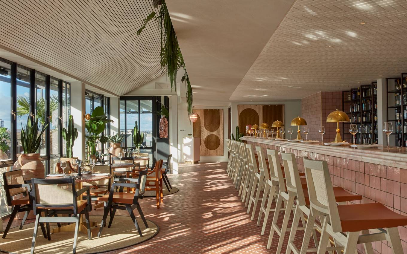 A hotel bar elegantly surrounded by lush greenery, creating a serene and inviting atmosphere for guests.